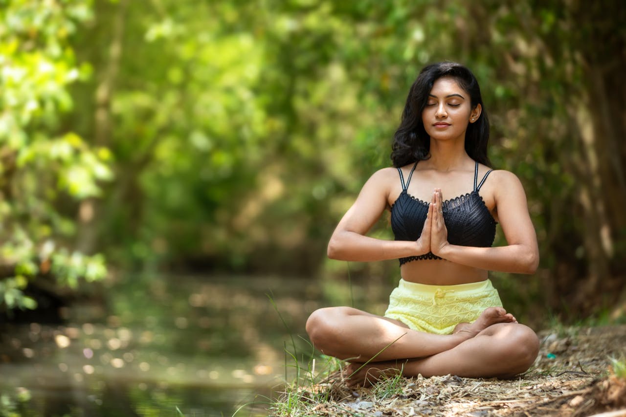 Woman practicing yoga outdoors by a serene water body, embodying peace and mindfulness.