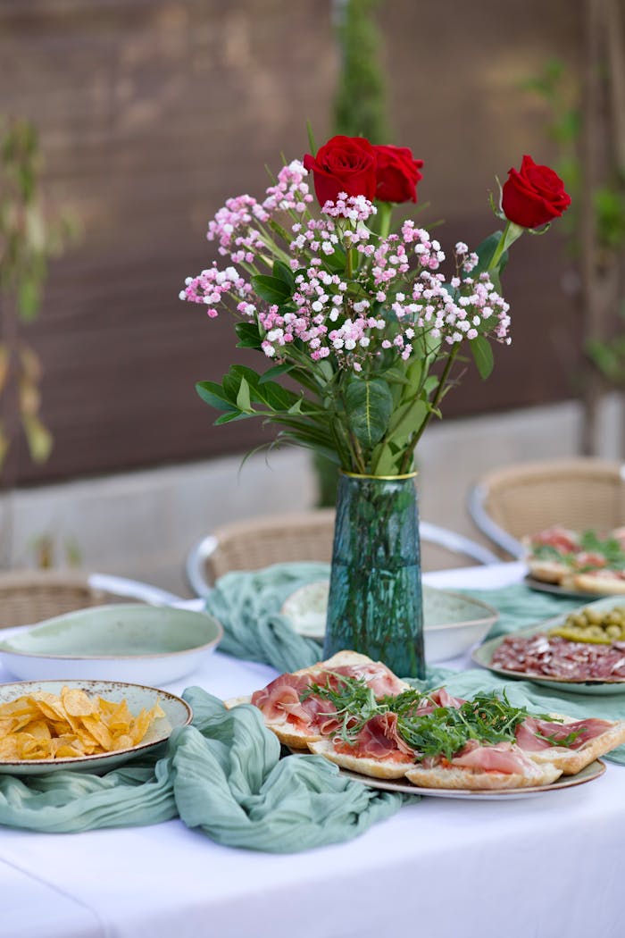 A beautifully set outdoor dining table adorned with a floral centerpiece and delicious food platters.