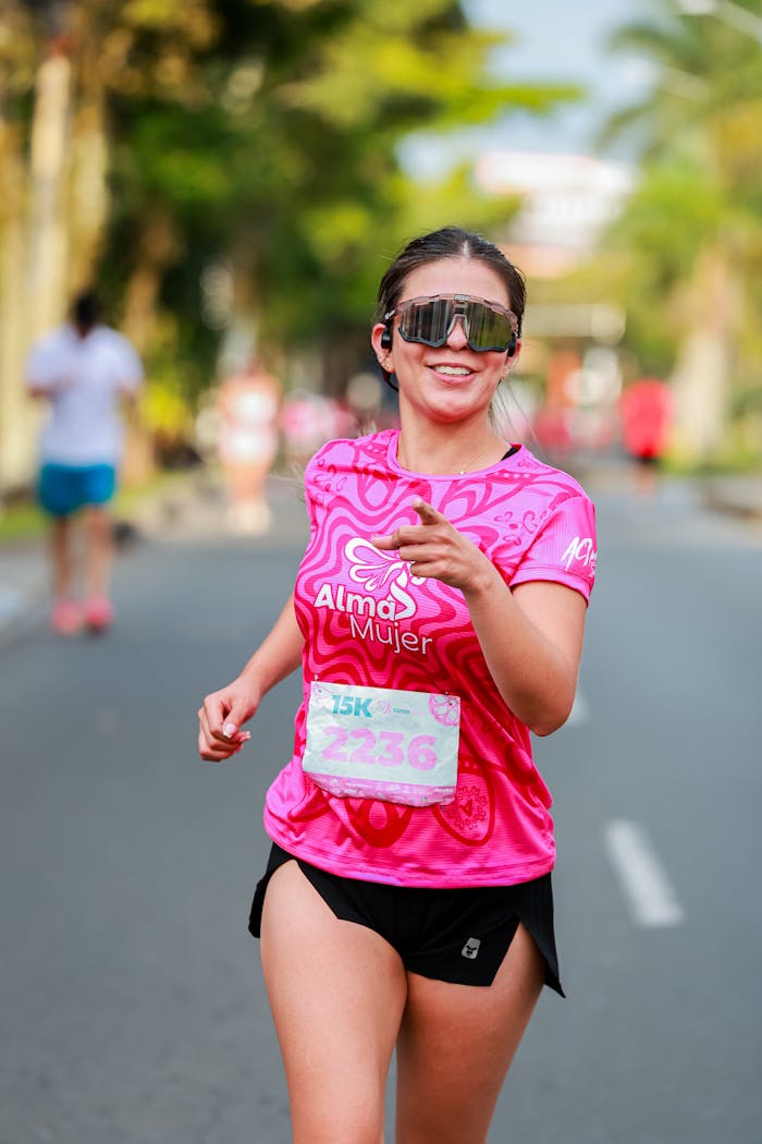 The Art of Drawing Readers In: Your attractive post title goes here A smiling woman running in a 15K race, wearing a pink 'Alma Mujer' shirt and sunglasses.