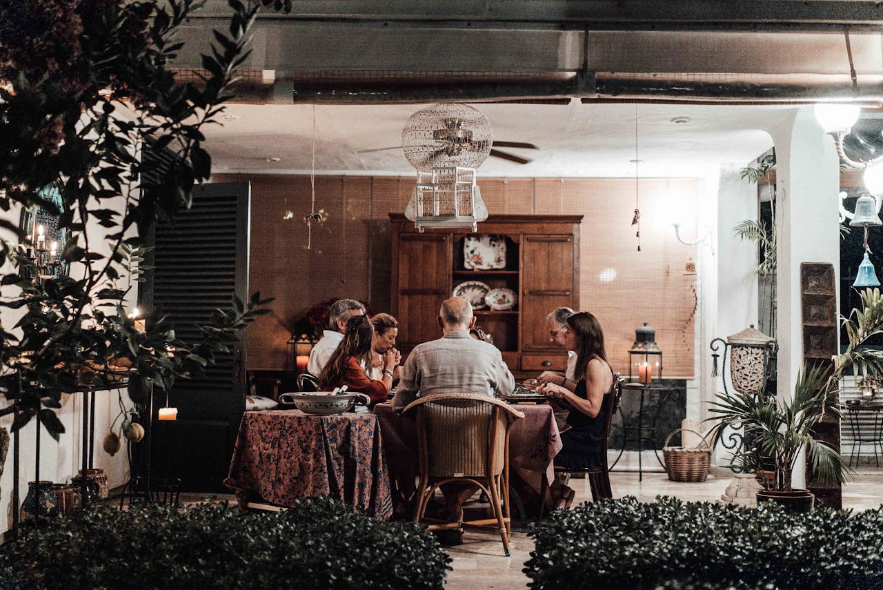Family sitting at served table and having meal together under chandelier and fan in cozy home